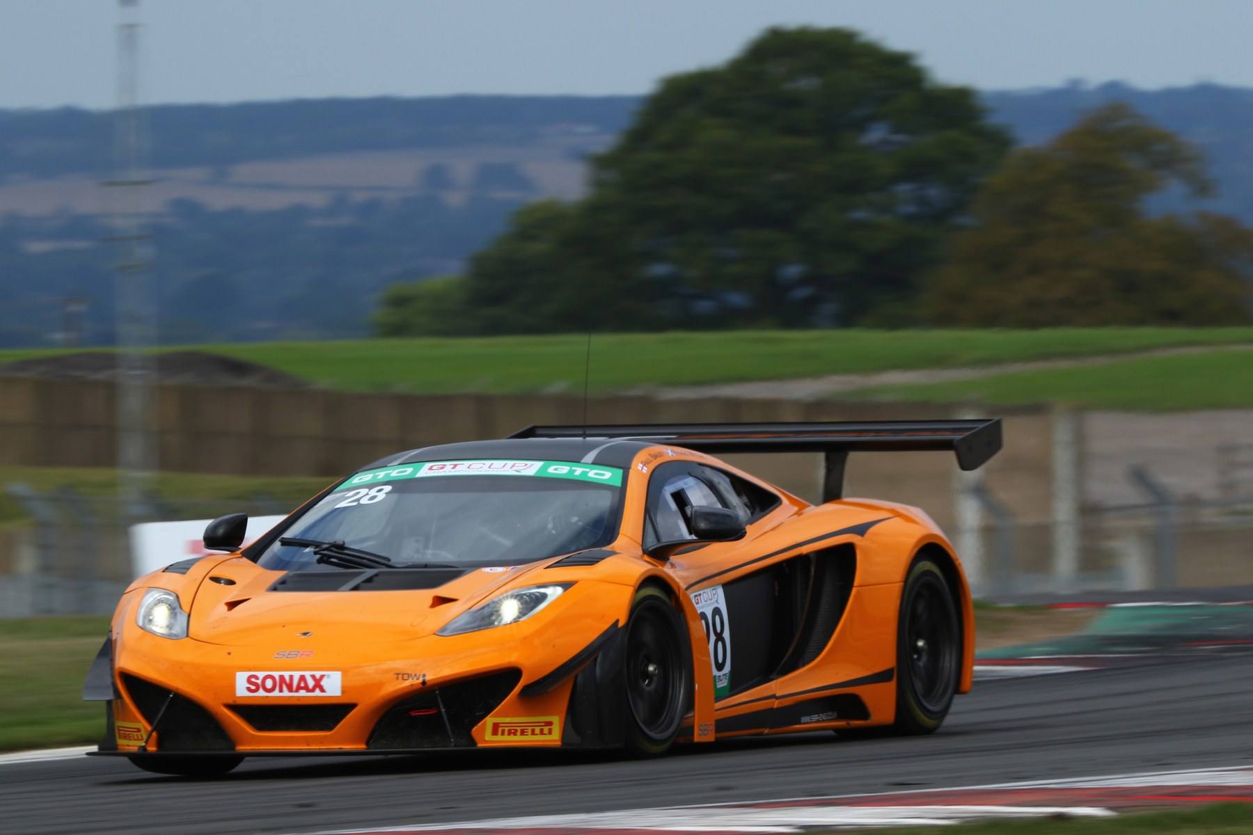 The orange SBR McLaren MP4-12C GT3 Can-Am Edition, number 28, at speed at Donington Park