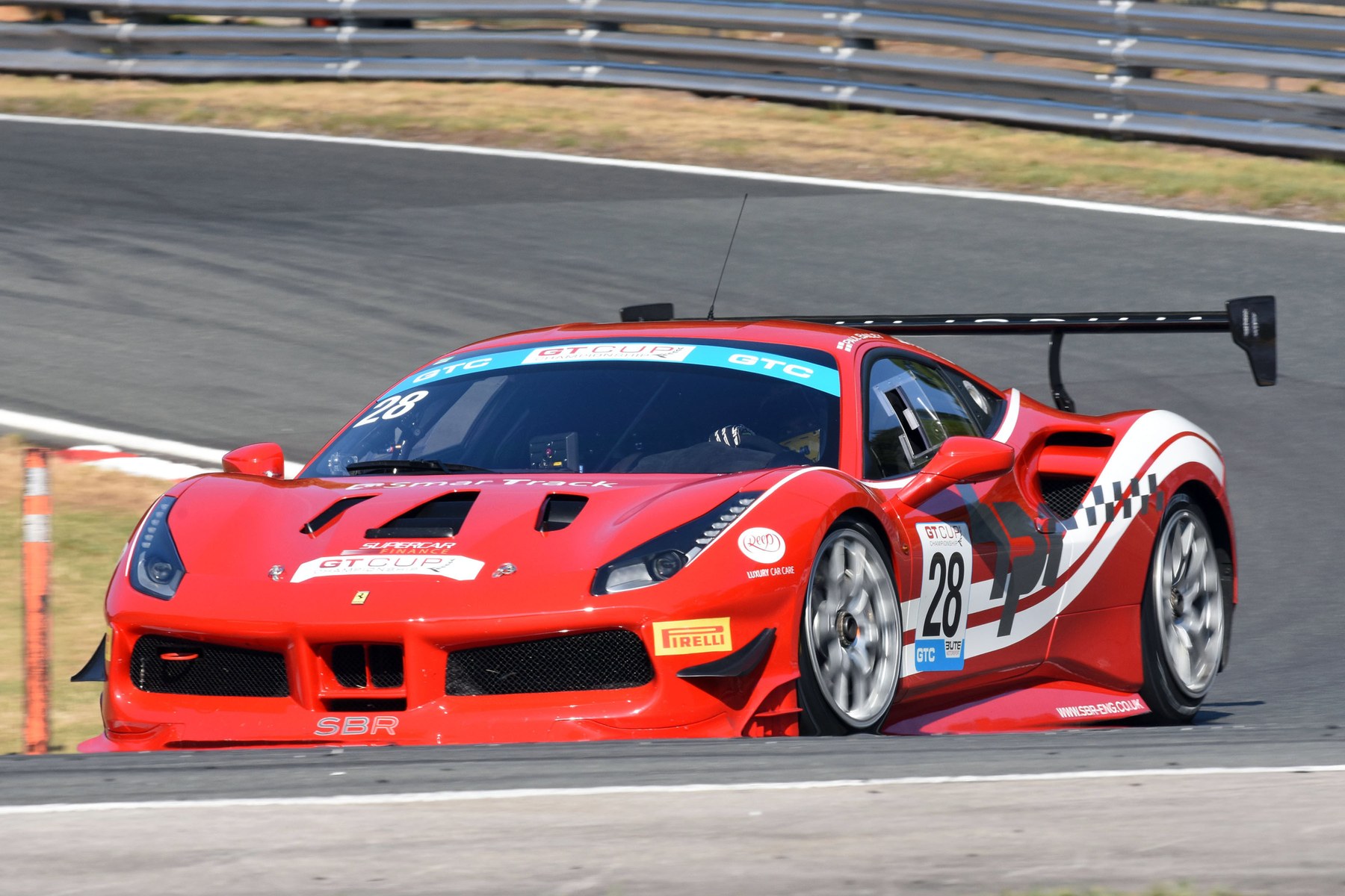 The SBR Ferrari 488 Challenge, number 28, in red with white stripes cornering at Oulton Park in the GT Cup