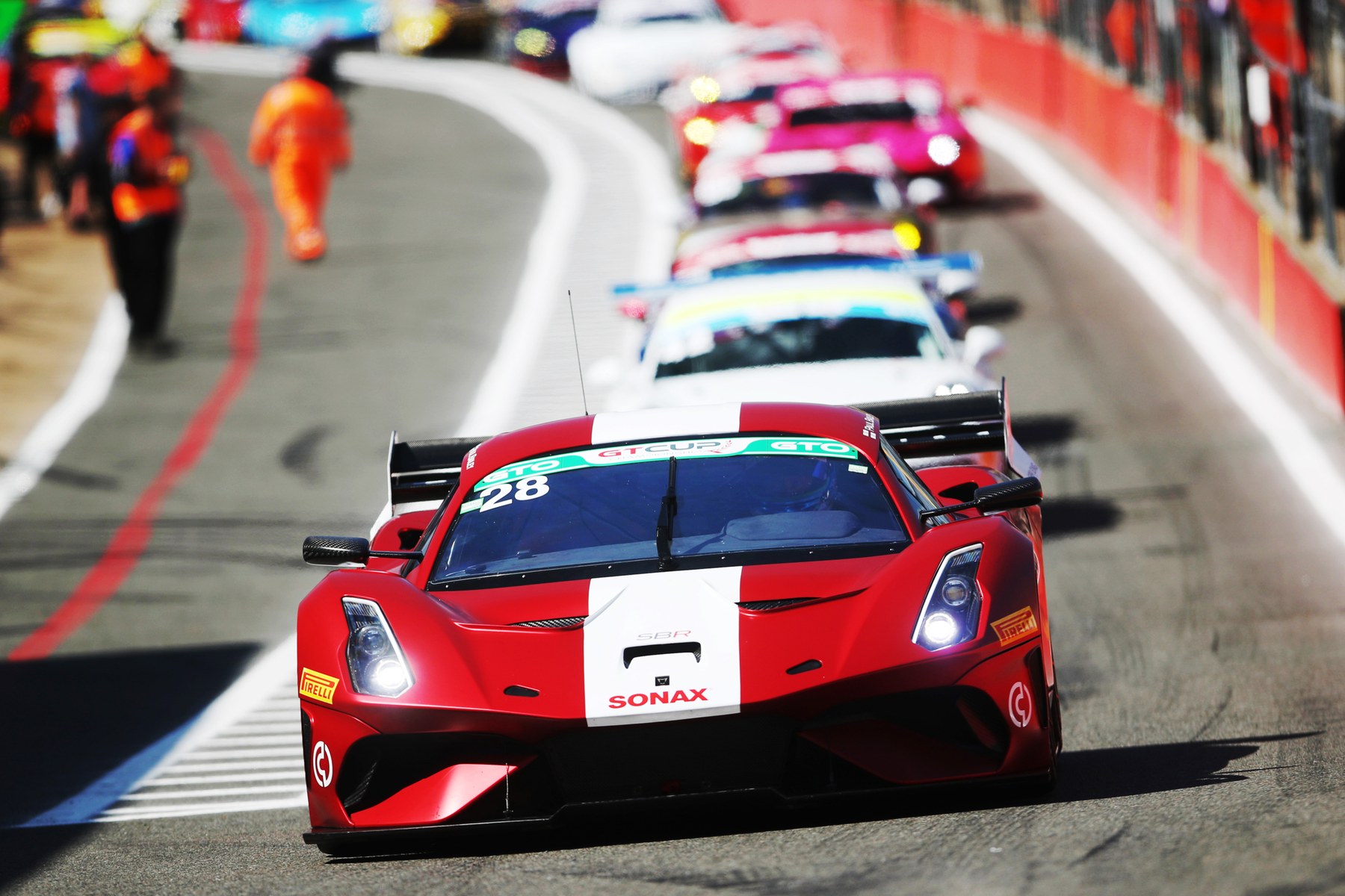 The SBR run Brabham BT62 in red and white livery, number 28, leading a pack of GT Cup cars through a corner at Brands Hatch