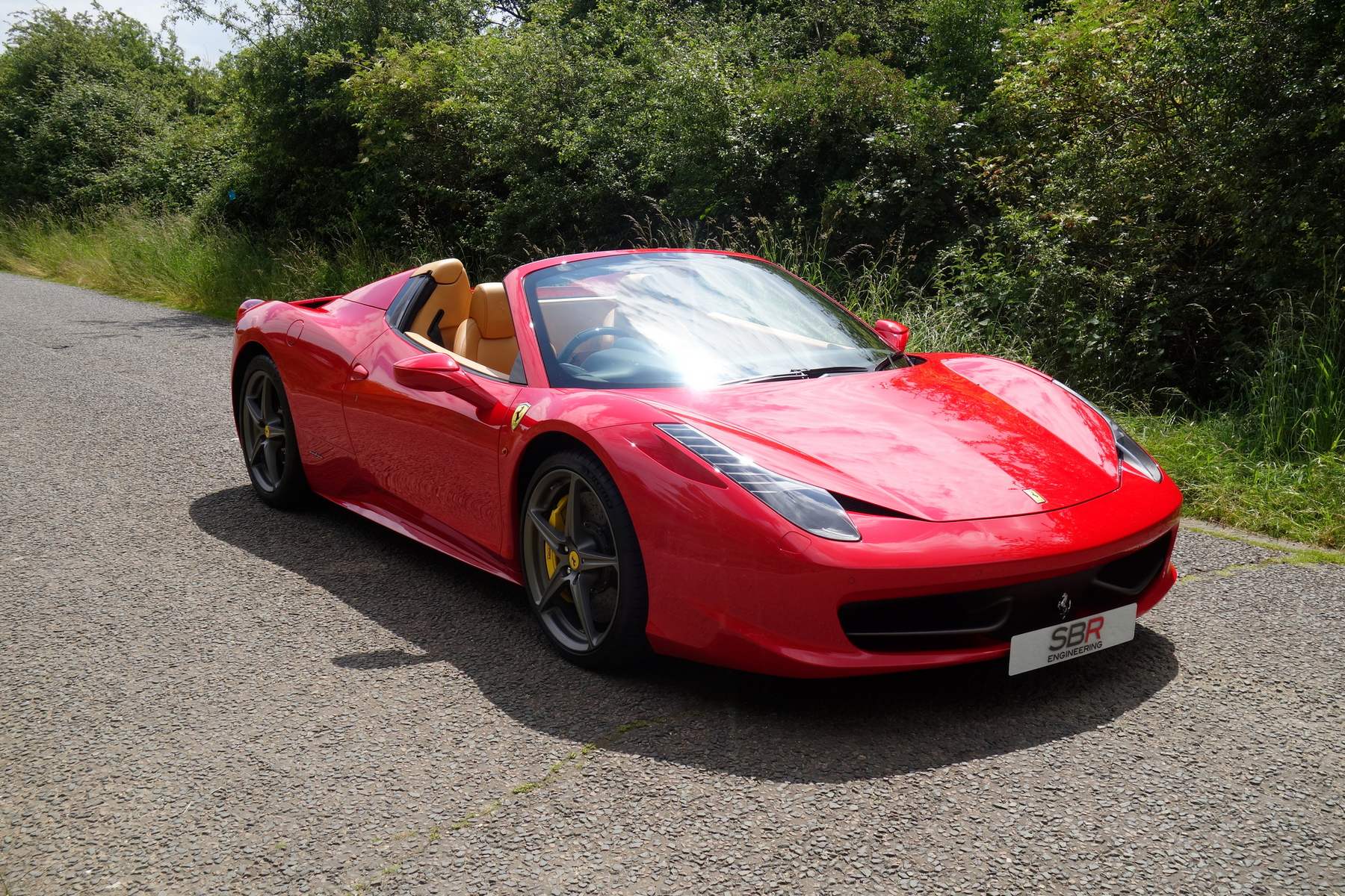 A red Ferrari 458 Spider photographed by SBR on a quiet country lane, one of the cars sold through SBR Engineering