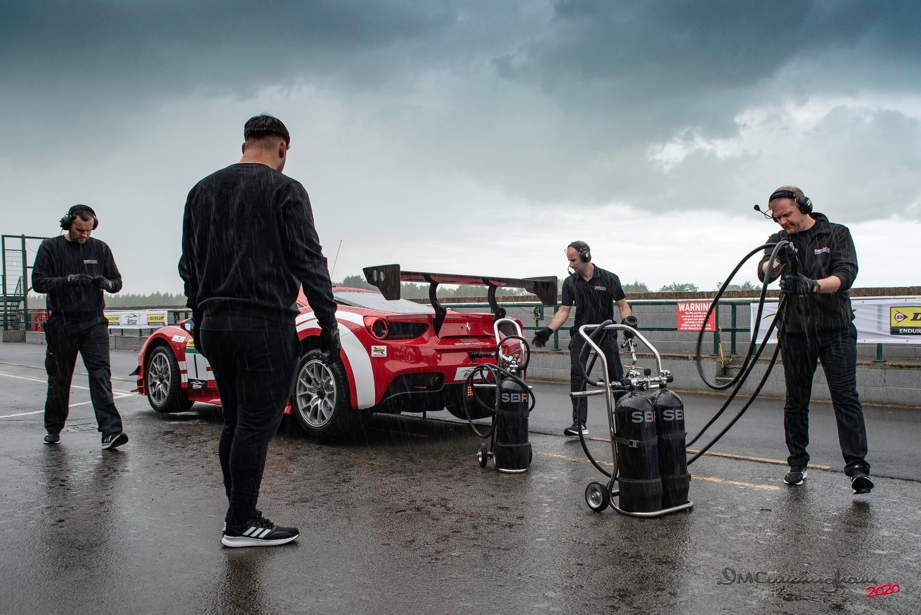 The SBR team in the wet pit lane at Croft with the red and white Ferrari 488 Challenge and fuel rigs during a test day
